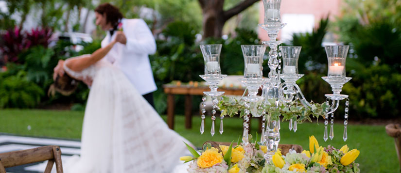 Intricate flower arrangement and crystal candle holder in the foreground with dancing newlyweds in the background at the Truman Little White House, Key West, FL