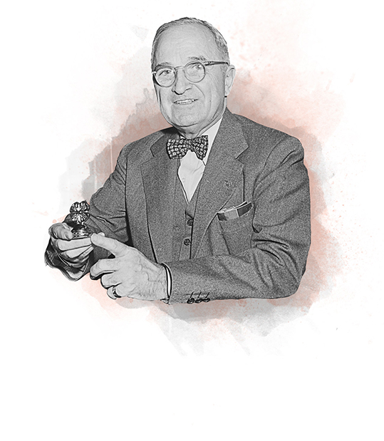 President Truman retiring holding four leaf clover paper weight at desk