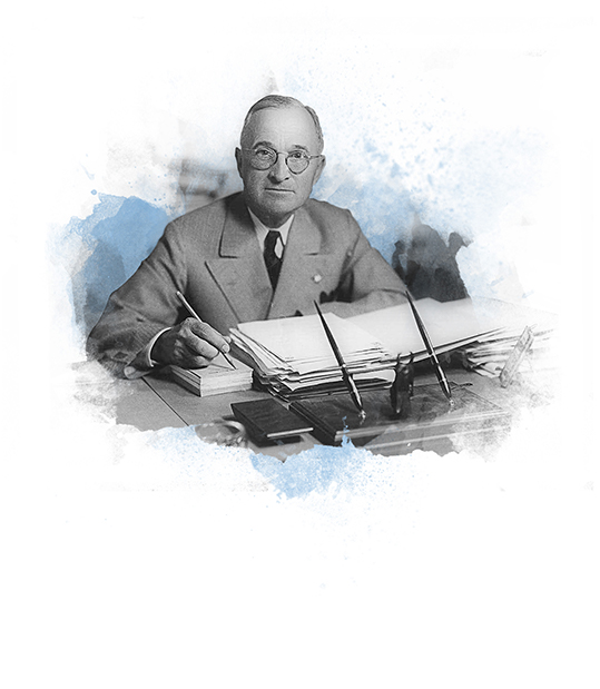 Post World War 2 Harry Truman seated at desk signing GI bill
