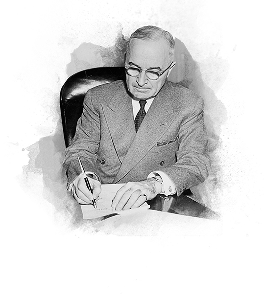Truman at desk signing declaration that the Korean War has ended